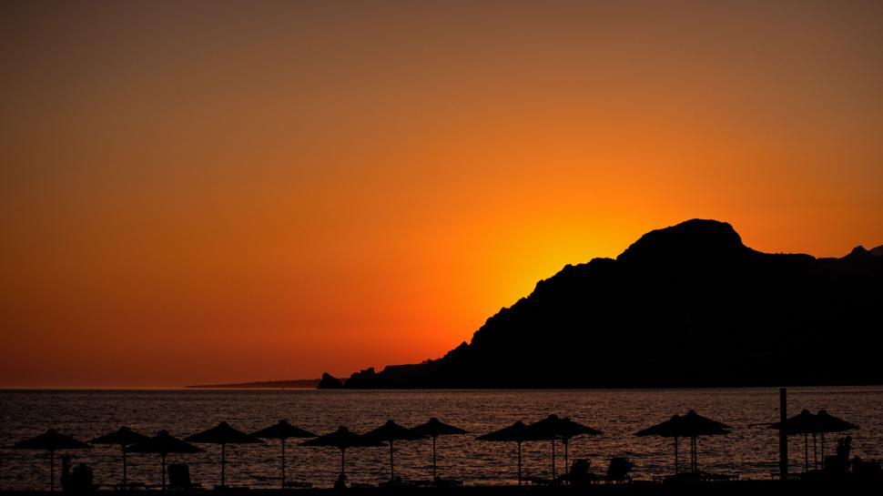 Free Image of Mesmerizing sunset over scenic beach with umbrellas 