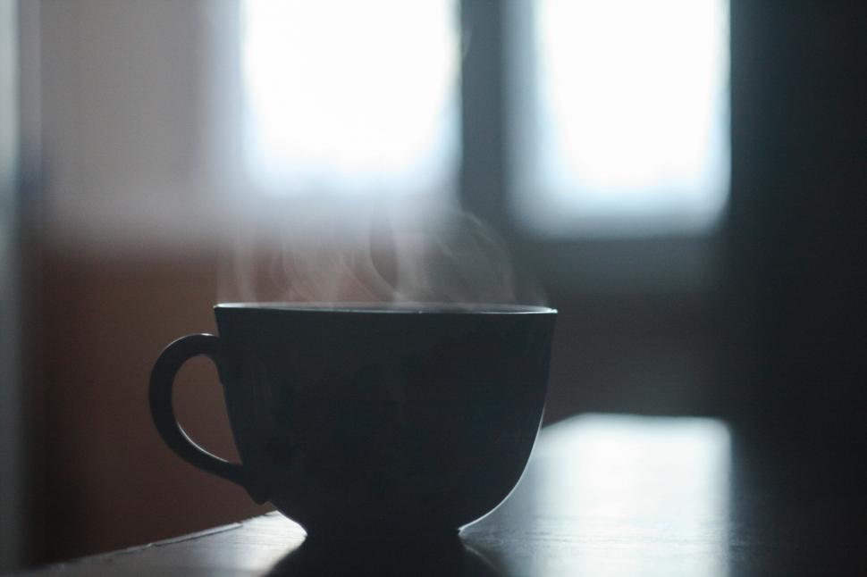 Free Image of Steaming dark cup on a table with soft diffuse lighting. 