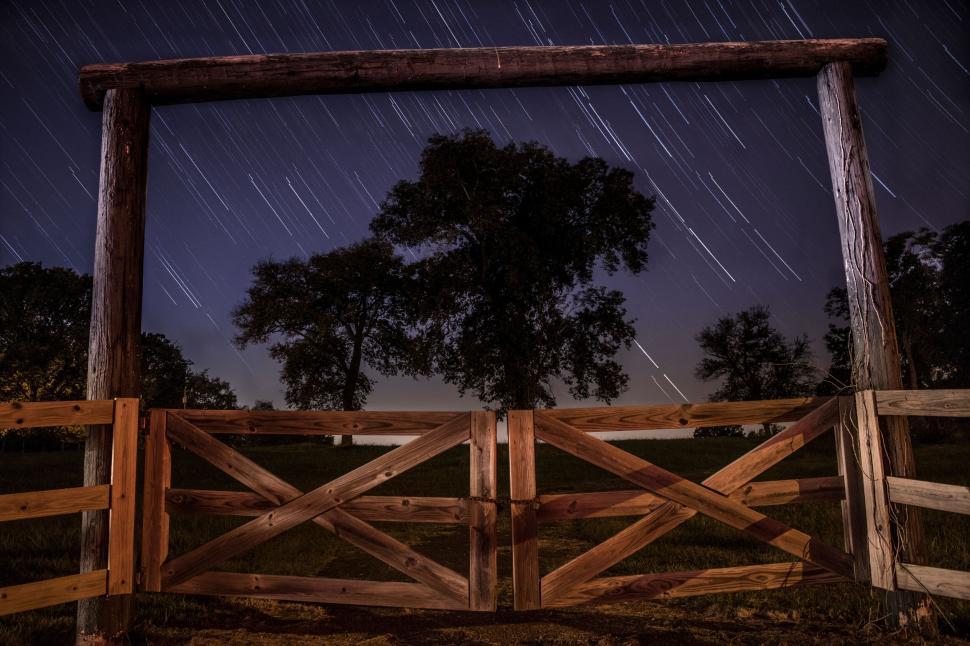 Free Image of Wooden gate under a starry sky with trailing star lights 