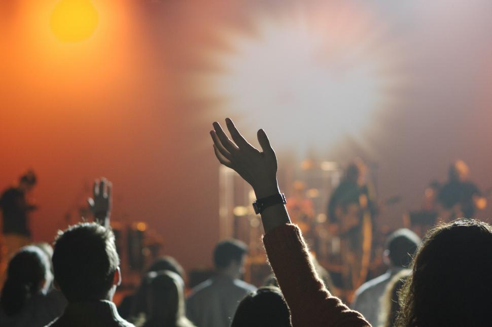 Free Image of Concert crowd with hands raised, vibrant stage lighting. 
