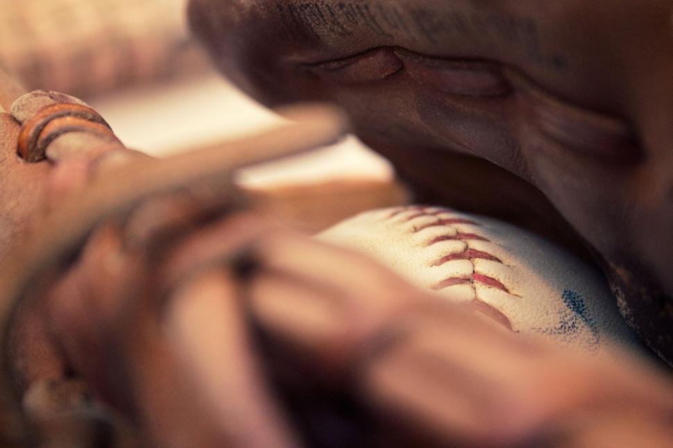 Free Image of Baseball glove tightly gripping a white baseball below. 