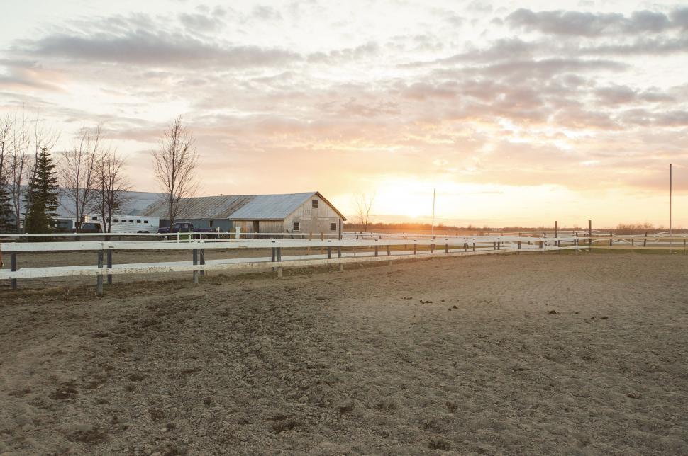 Free Image of Sunset casting warm light over a rural farm landscape 