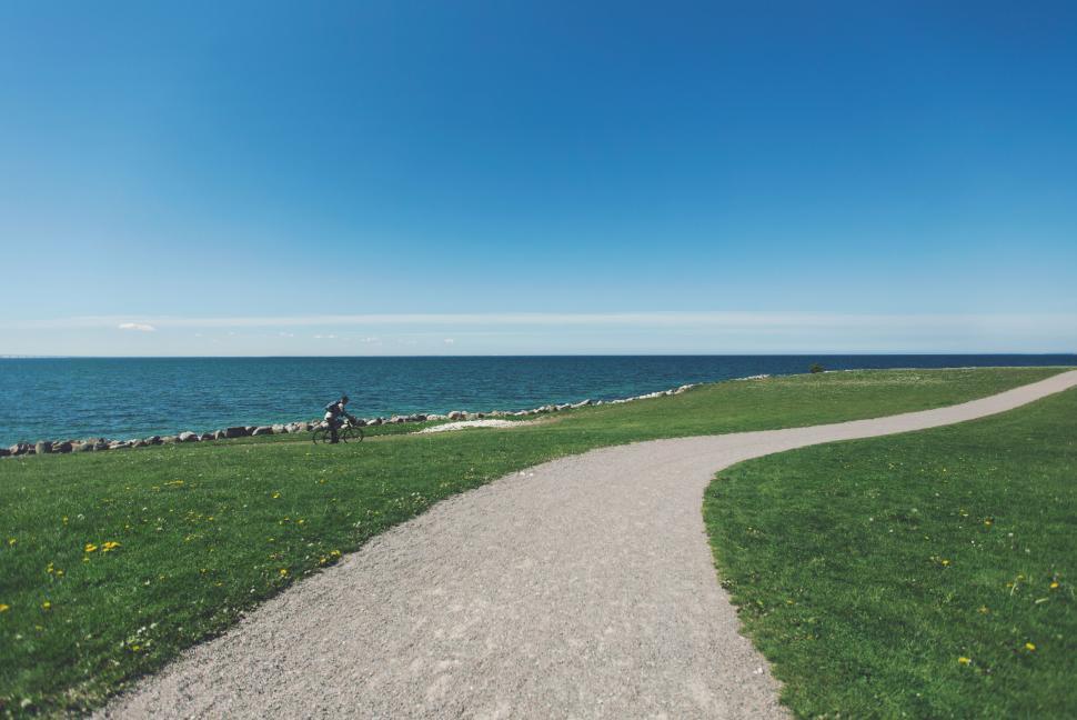 Free Image of Clear blue sky over a path leading to a calm ocean. 