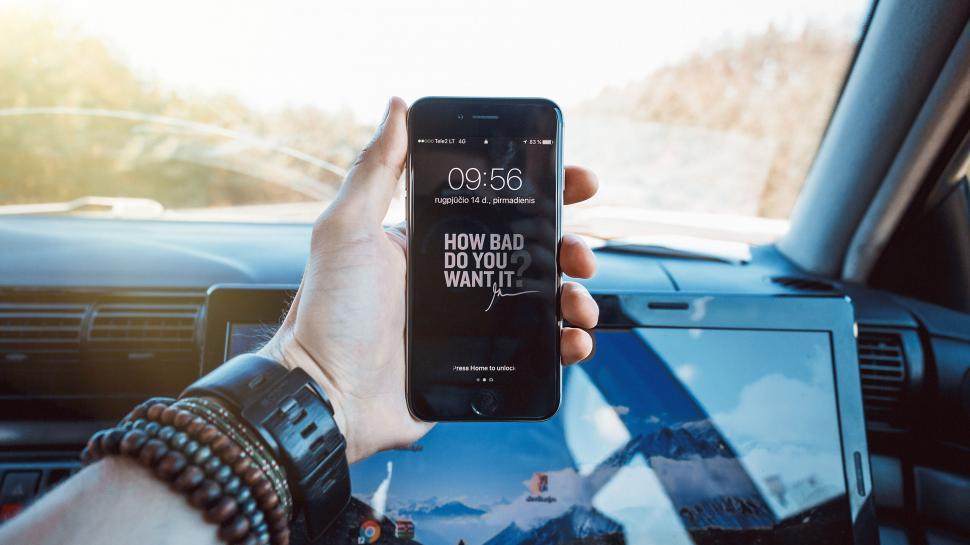 Free Image of Hand holding phone with motivational quote in car. 