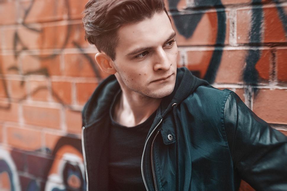 Free Image of Detailed casual outfit with jacket against graffiti wall. 