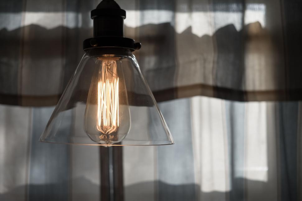 Free Image of Vintage lightbulb glowing against soft, diffused curtain 