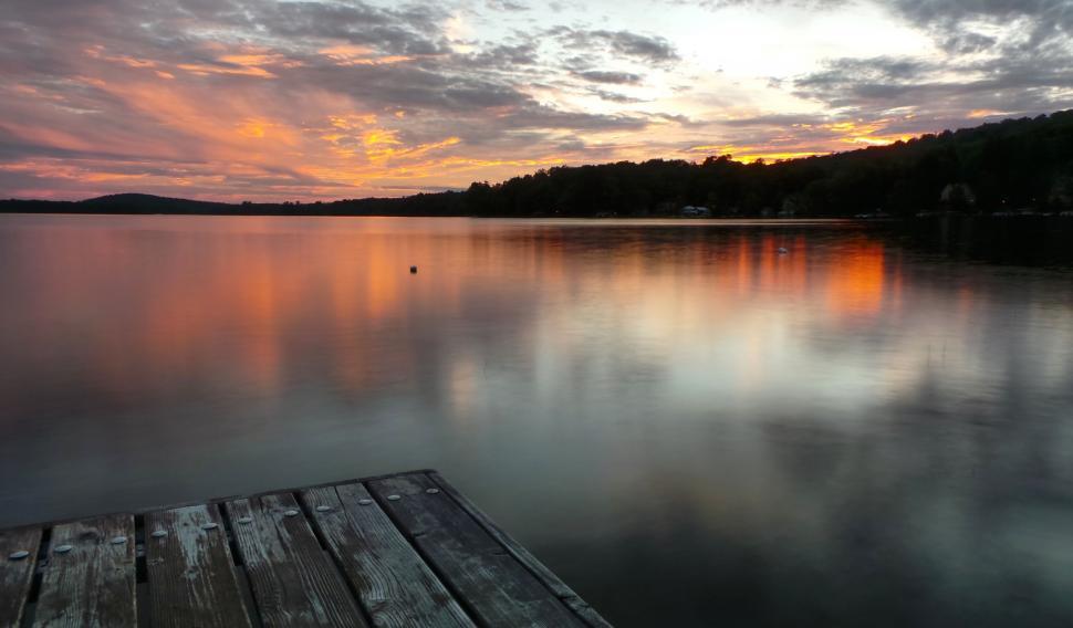 Free Image of Colorful sunset over calm lake with wooden pier. 