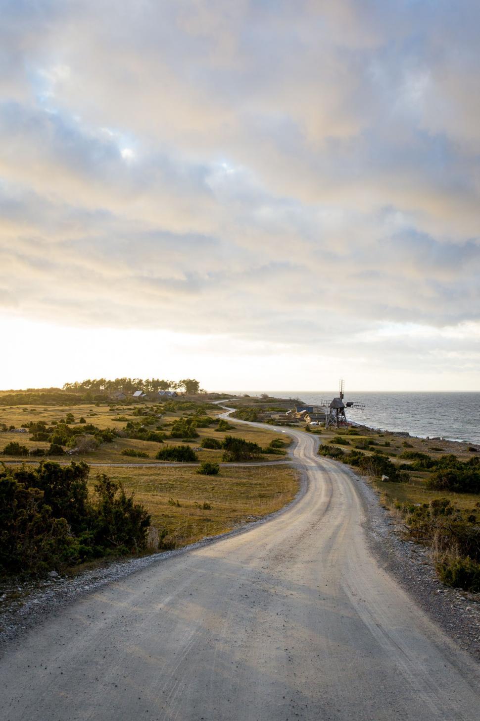 Free Image of Winding country road leading to seaside windmill scene 