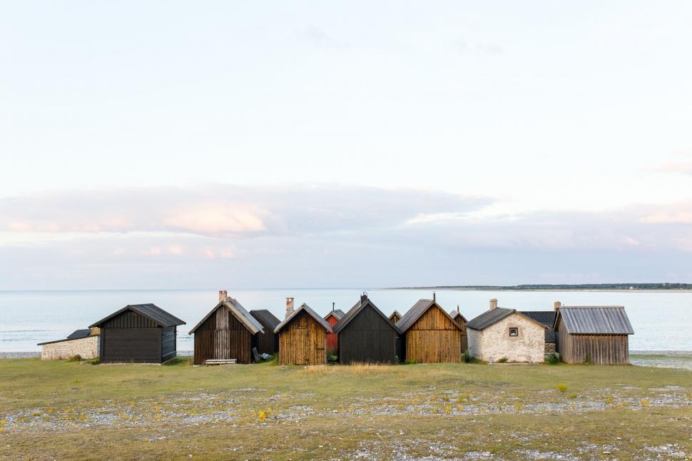 Free Image of Row of rustic beach huts facing calm sea and horizon 