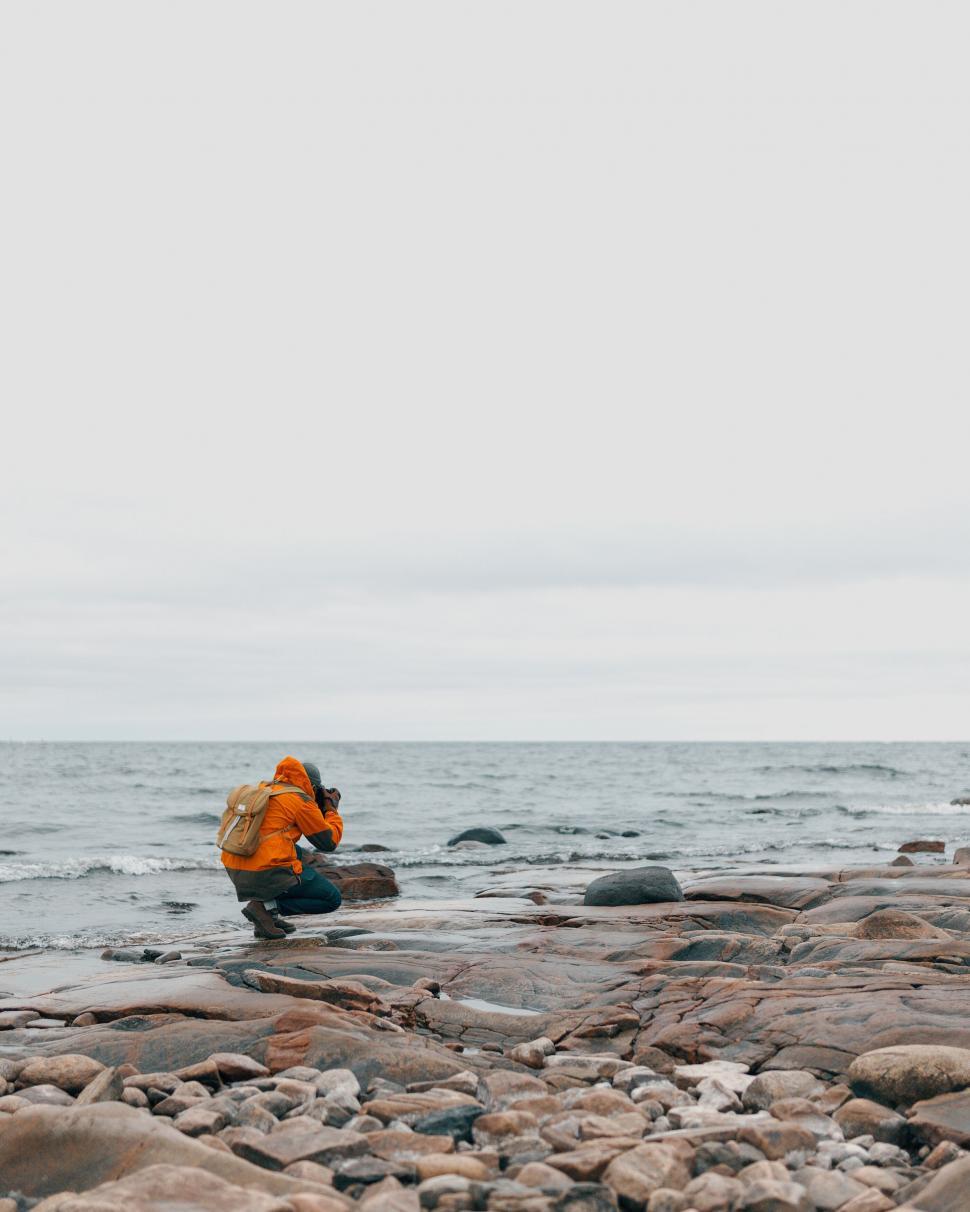 Free Image of Photographer in orange jacket capturing moments by sea 
