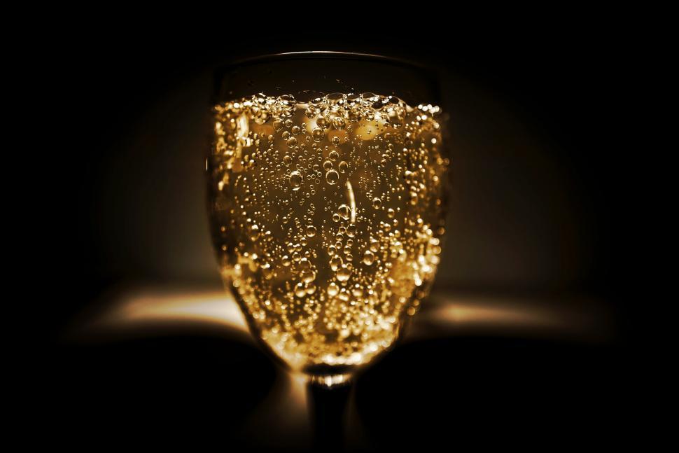 Free Image of Glass of champagne with bubbles illuminated against black 