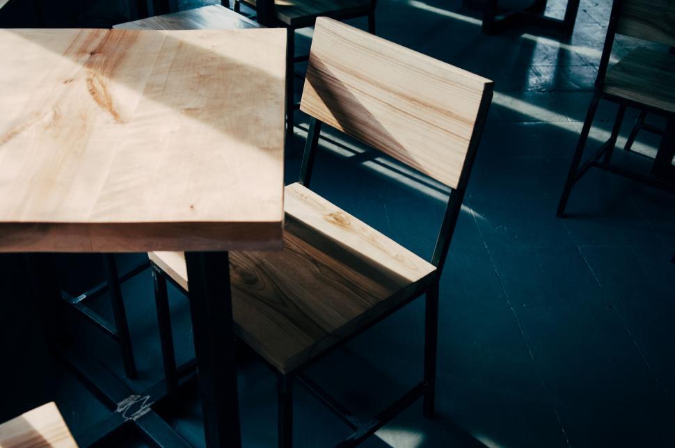 Free Image of Empty wooden chair and table in a dimly lit room 