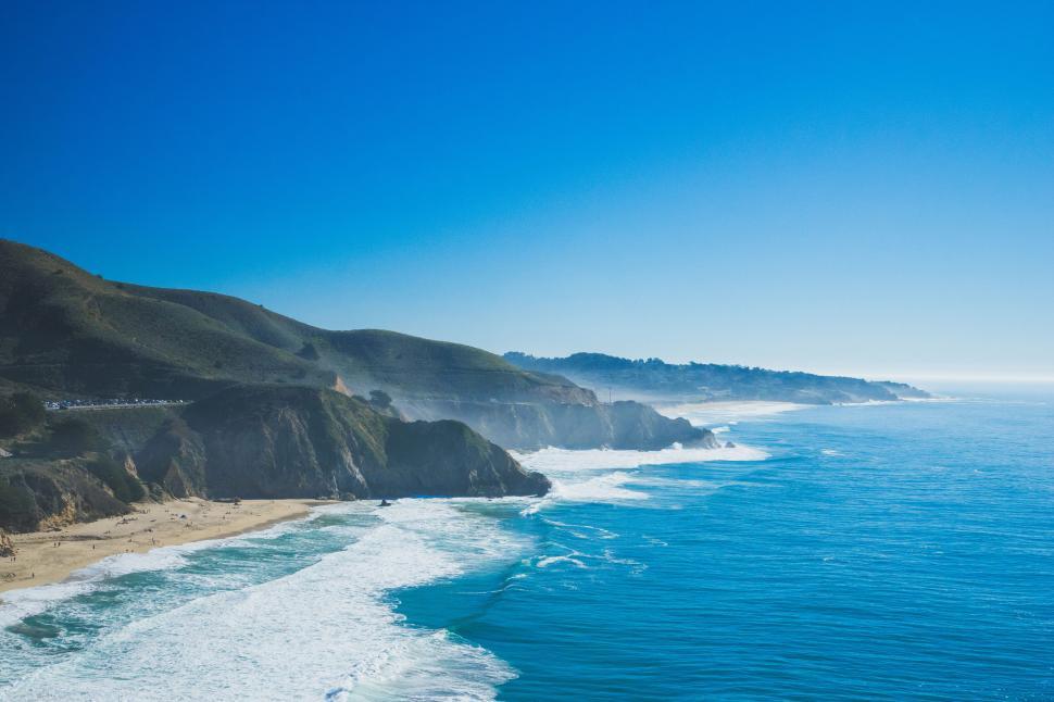 Free Image of Vast beach coastline with mountains under a clear sky 