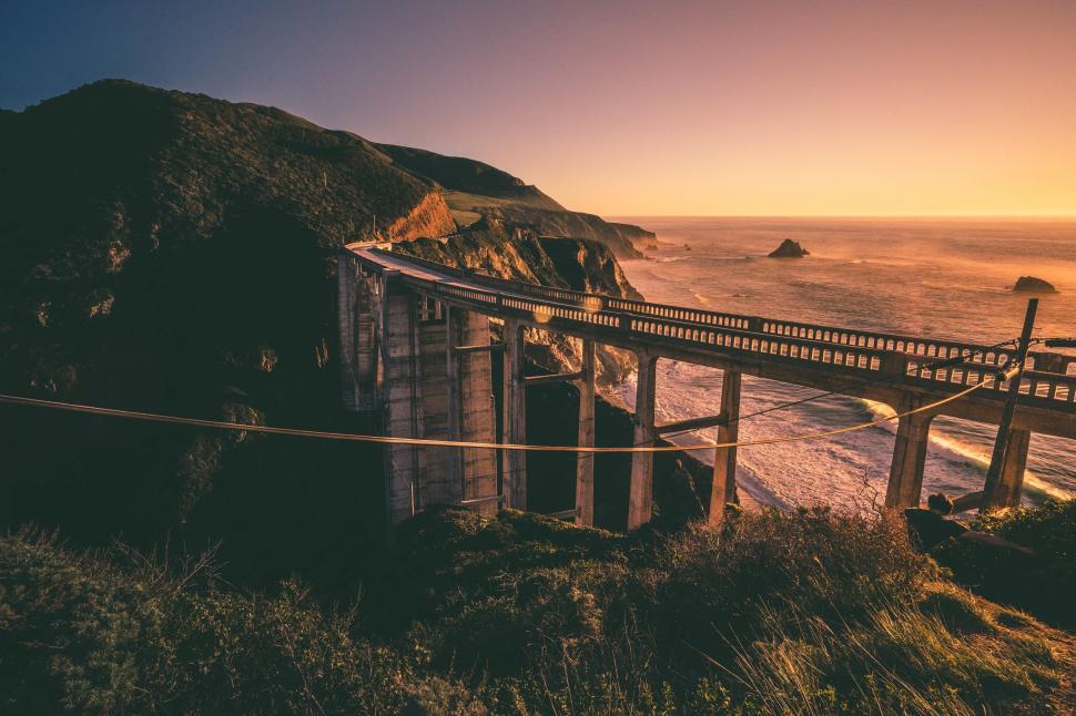 Free Image of Sunset casts hues over iconic coastal bridge and sea. 