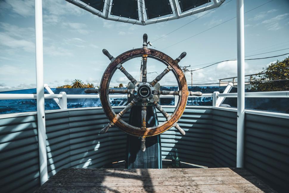 Free Image of Rusty ship wheel on a boat against a clear sky 