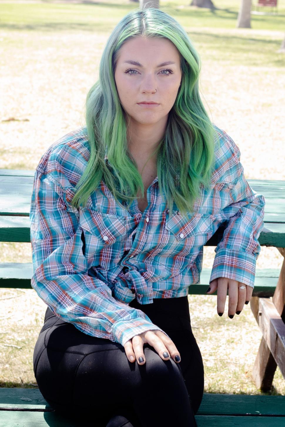 Free Image of Woman with green hair in plaid shirt at a park 