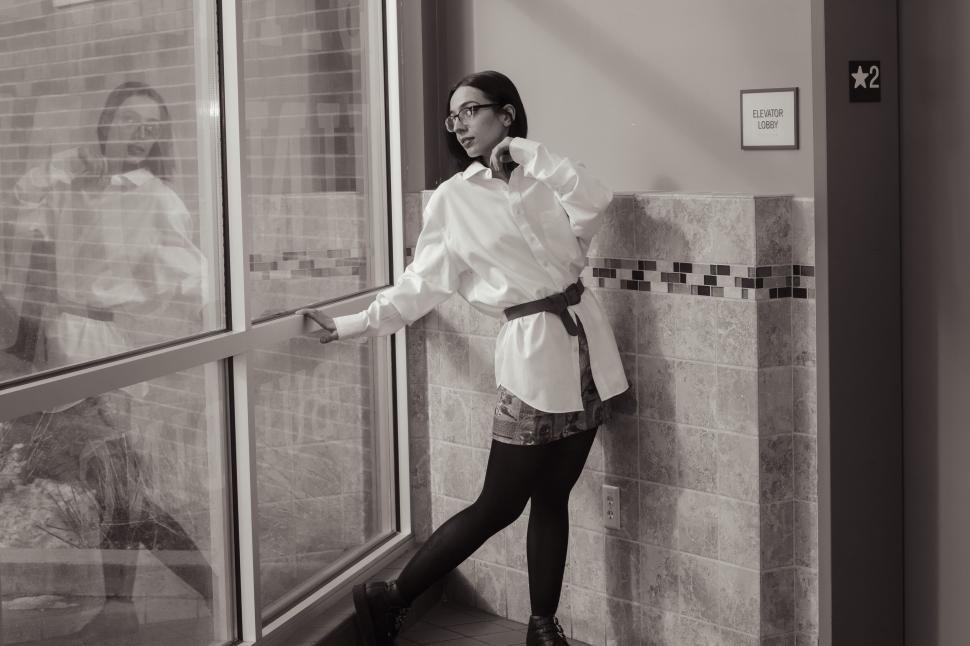 Free Image of Stylish woman posing in front of large glass window 