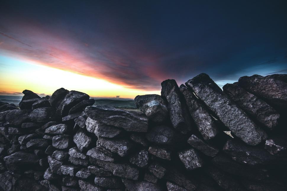 Free Image of Sunrise over a stone wall with a dramatic sky background. 