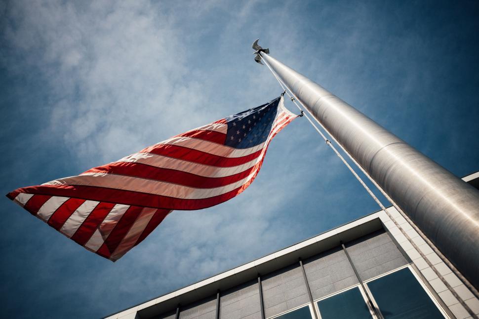 Free Image of American flag waving tall against a clear blue sky 