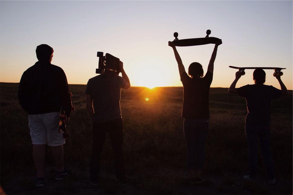 Free Image of Group of friends with skateboards silhouetted at sunset 