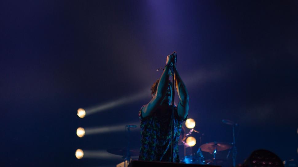 Free Image of Performer singing passionately on a lit concert stage 