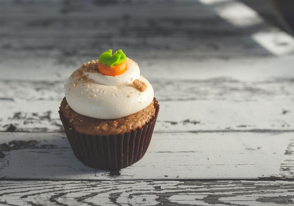 Free Image of Carrot cupcake with frosting on a rustic wooden surface 