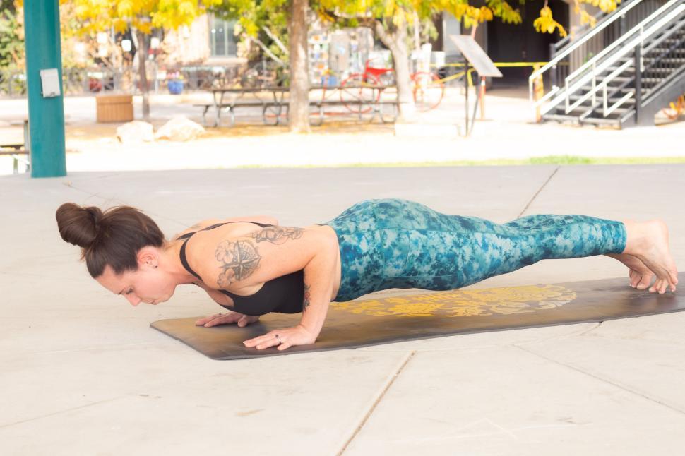 Free Image of Woman in plank pose on a yoga mat in an outdoor area 