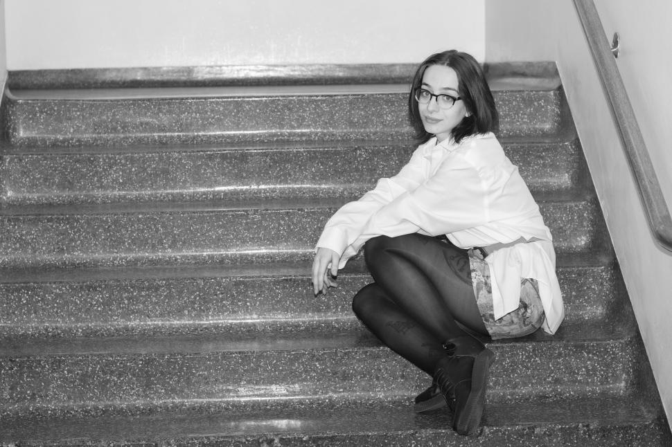 Free Image of Woman squatting on staircase in dimly lit environment 