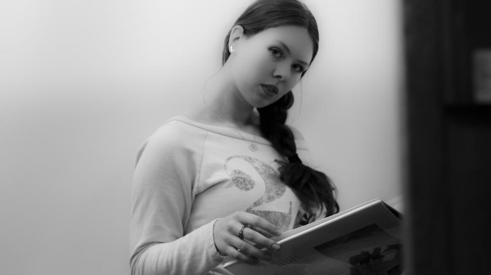 Free Image of Woman reading a book leaning against a wall 