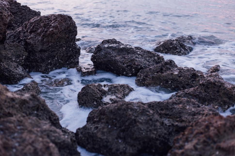 Free Image of Rugged coastal rocks with foam forming on ocean water. 
