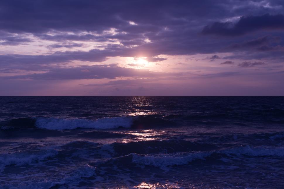 Free Image of A stunning sunset over the ocean with purple hues. 