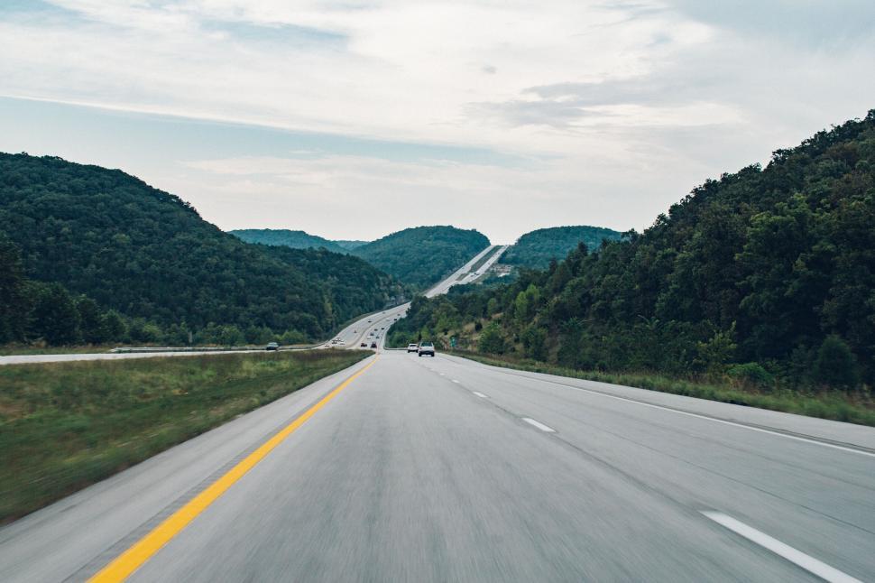 Free Image of Open highway stretching between lush green hills, serene. 