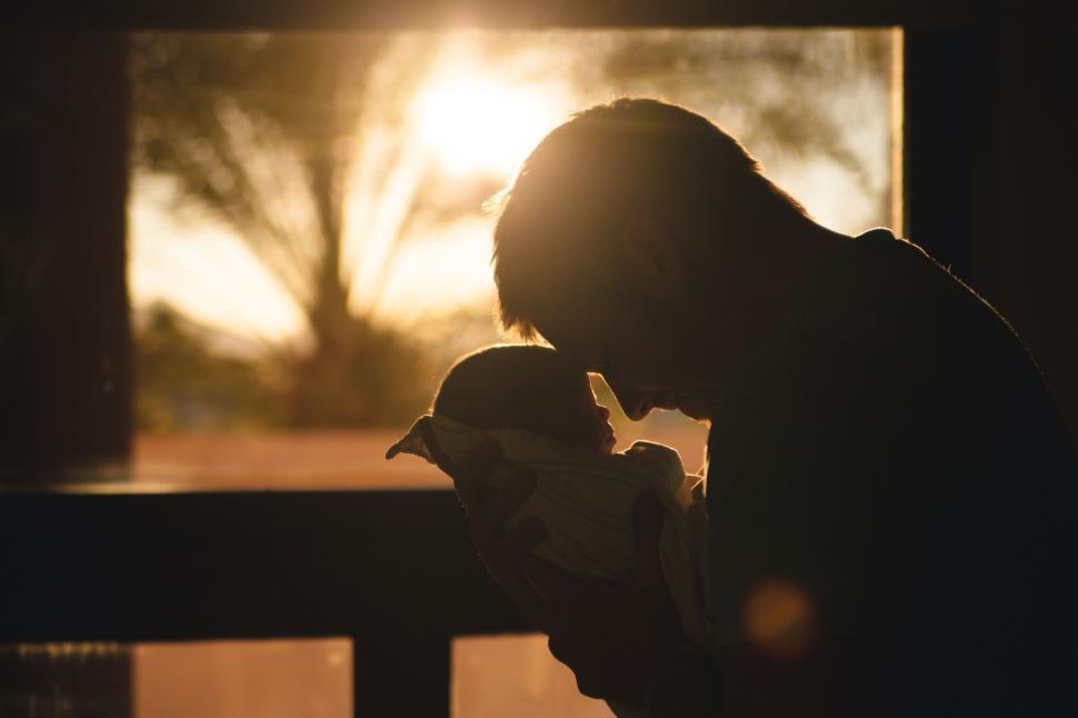 Free Image of Silhouette of parent and child against setting sunset. 