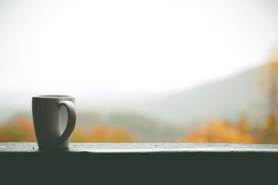 Free Image of White ceramic coffee cup on ledge with blurred background 