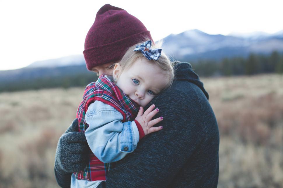 Free Image of Person holding baby in plaid shirt with scenic view 