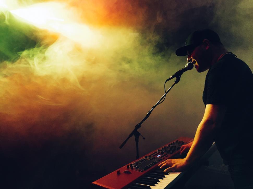 Free Image of Musician playing keyboard in smoke-filled glowing stage 