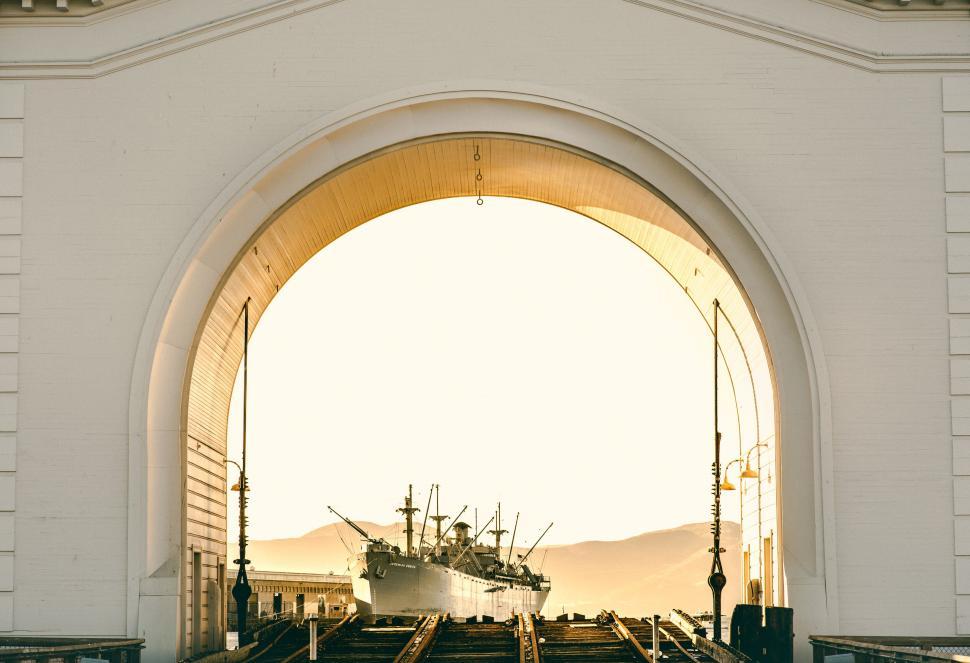 Free Image of Historic ship docked under majestic arched structure 