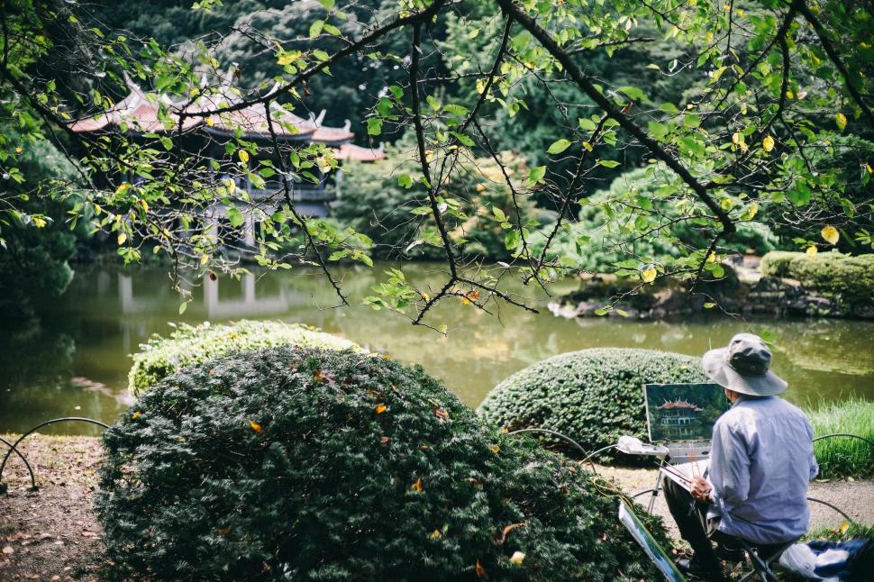 Free Image of Artist painting in serene Japanese garden with pond view 