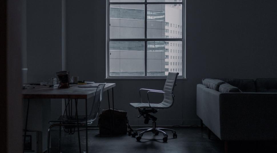 Free Image of Dimly lit modern office with cityscape view outside. 