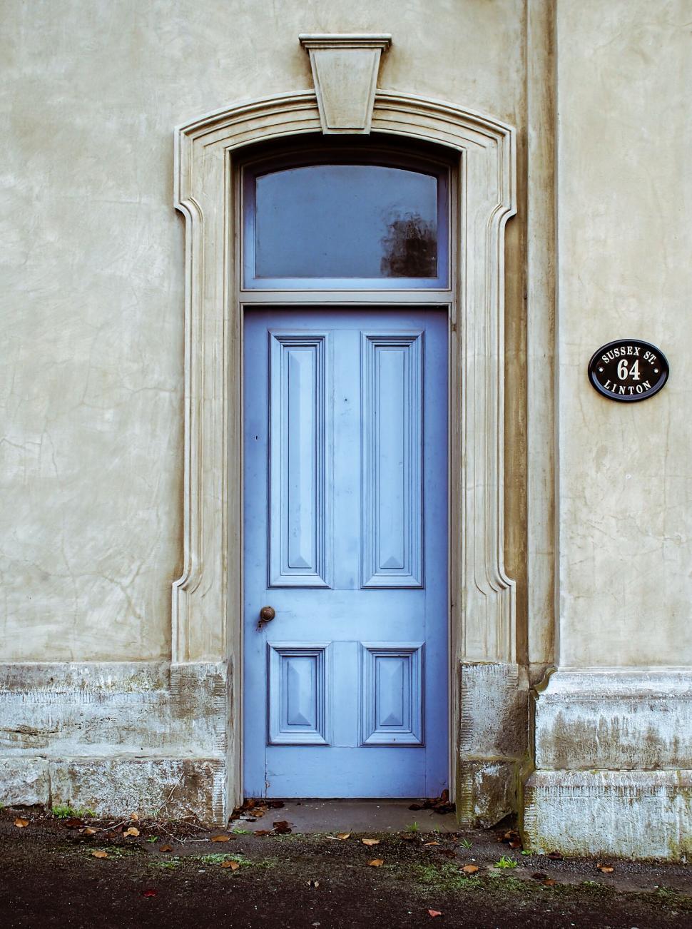 Free Image of Vintage-style blue door set in an old wall with a plaque reading 64. 