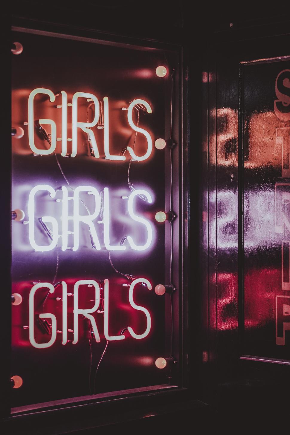Free Image of Neon sign with repeated word  GIRLS  glowing in nighttime setting. 