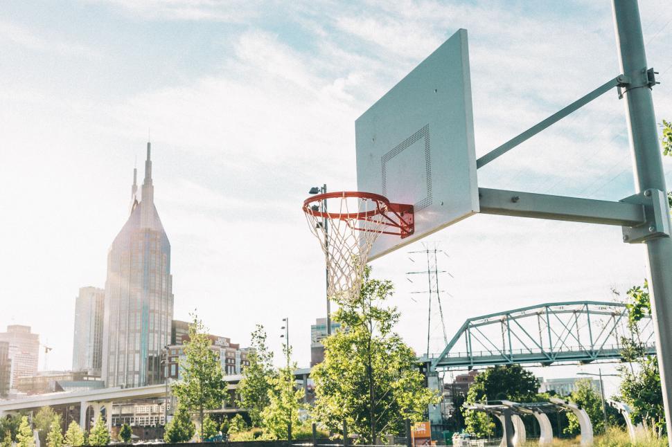 Free Image of Outdoor basketball hoop with cityscape and bridge background 