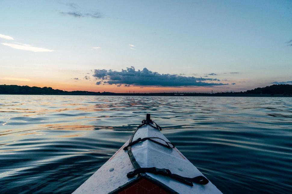 Free Image of Kayaking on a calm lake during sunset with a distant horizon 