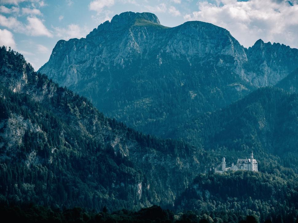 Free Image of Majestic castle nestled among lush green mountains and trees 