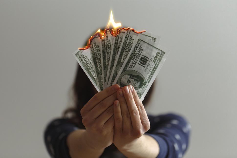 Free Image of Person holding burning one hundred US dollar bills forward 