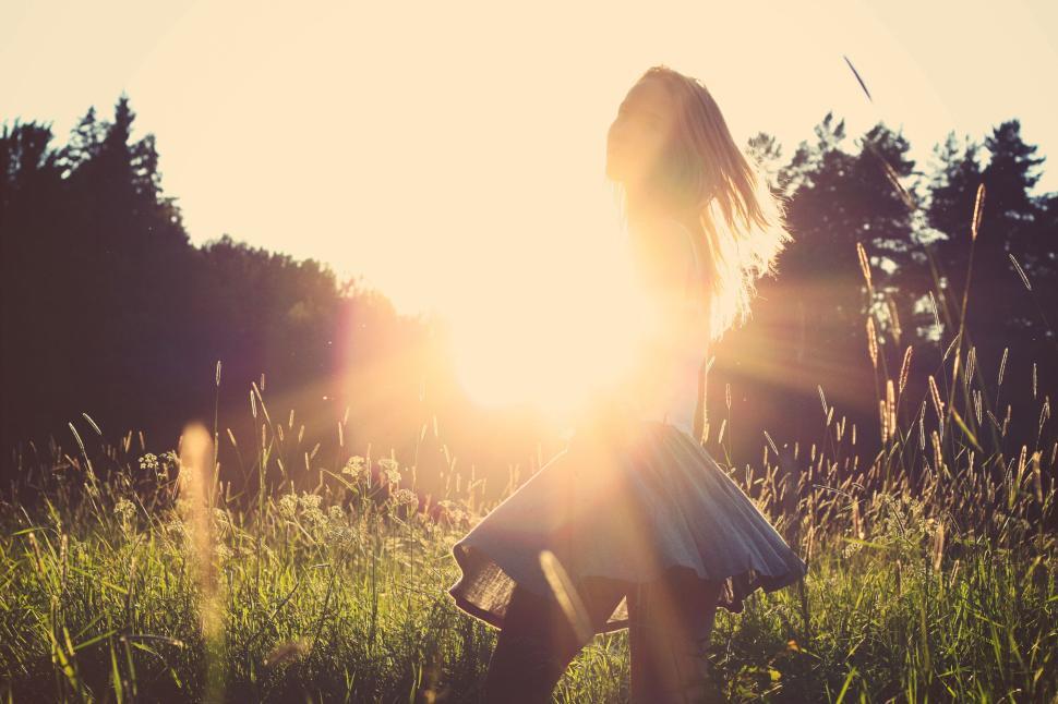 Free Image of Silhouette of girl dancing in field with bright sunset behind. 