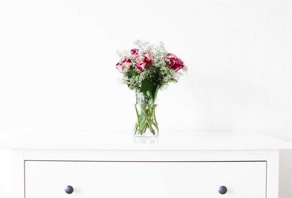 Free Image of Elegant bouquet of flowers in glass vase on minimalist dresser. 