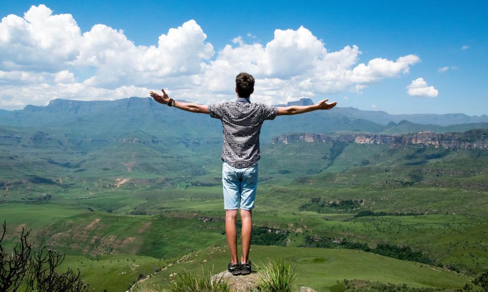 Free Image of Man with arms open wide embraces expansive green mountain valley 