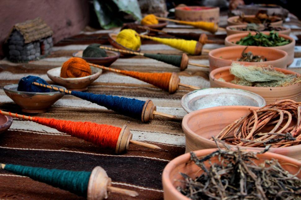 Free Image of Colorful traditional artisan yarn and spindle display on woven mat. 