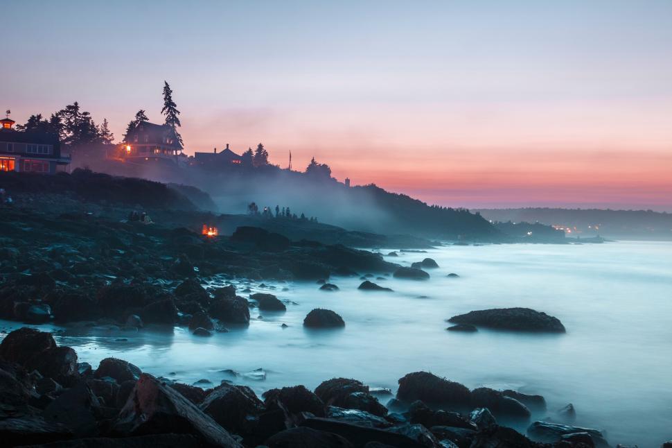 Free Image of Coastal landscape at dusk with mist covering the rocky shore 